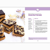 Eine Seite aus dem Fettverlust Fibel Kochbuch zeigt ein Rezept für Erdnussbutterriegel mit einem Foto von Schokoladen- und Nussquadraten, aufgedruckten Zutaten und Arbeitsschritten sowie Lavendelblüten-Dekor - perfekt für einen abnehmfreundlichen Snack.