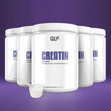 Fünf weiße Creatin Monohydrat-Behälter sind auf einem lilafarbenen Hintergrund angeordnet, mit einem Messlöffel Kreatinpulver auf der Vorderseite - ideal für Sportler und perfekt, um Ihr Training mit hochwertigem Creatin Monohydrat zu unterstützen.