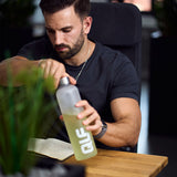 Mann am Schreibtisch öffnet den QLF Hydration Shaker (100% off) mit Getränk neben offenem Notizbuch