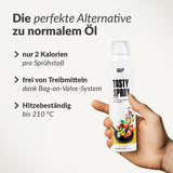 Eine Hand hält eine Dose mit Tasty Spray. Der Text hebt die 2 kcal pro Sprühstoß, das treibgasfreie Bag-on-Valve-System, die präzise Dosierung und die Hitzebeständigkeit bis zu 210°C hervor. Auf der Dose sind bunte Lebensmittelgrafiken abgebildet.