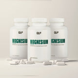 Drei weiße Dosen mit der Aufschrift "Magnesium" steht aufrecht inmitten von weißen Kapseln und Pulver auf einer hellen Fläche. Das deutsche Etikett hebt hochwertiges Magnesium-Bisglycinat für optimale Bioverfügbarkeit hervor.