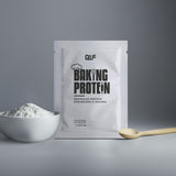 Eine Packung Backprotein steht aufrecht auf einer grauen Fläche neben einer weißen Schale mit Pulver und einem Holzlöffel. Ein fetter schwarzer Text und eine Grafik mit Kochmütze betonen seine Rolle bei Fitnessrezepten und beim Erreichen einer perfekten Konsistenz.