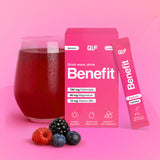 Ein Glas mit rotem Getränk steht neben einer rosafarbenen Benefit Hydration Box und einem Beutel mit frischen Himbeeren, Brombeeren und Blaubeeren im Vordergrund. Die Verpackung hebt die Elektrolytformel und den erfrischenden Geschmack hervor.
