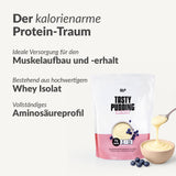 Auf der Verpackung eines proteinreichen Puddings mit der Aufschrift "Eiweiß" befindet sich ein Löffel Pudding mit Heidelbeeren. Der deutsche Text wirbt für Eiweiß zum Muskelaufbau, zur Unterstützung von Diäten und für eine lang anhaltende Sättigung.