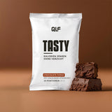 Tasty kalorienarmes Chocolate Fudge Geschmackspulver mit Kakaokeks-Stückchen, Portion und Packung vor braunem Hintergrund