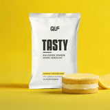 Tasty kalorienarmes Geschmackspulver Lemon Cheesecake mit Gebäckstückchen, Sachet und Dessert vor gelbem Hintergrund