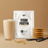 Ein Glas cremiger Vegan Protein Shake steht neben einer Packung mit der Aufschrift "Vegan Protein" und einem Stapel Kekse mit Vanilleschoten und Krümeln auf einem beigen Hintergrund - perfekt für einen leckeren Kick während der veganen Revolution.